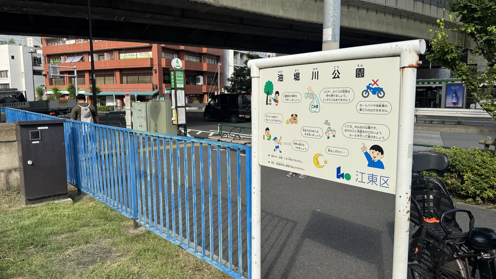 「油堀川公園」と書かれた利用案内板と青いフェンス