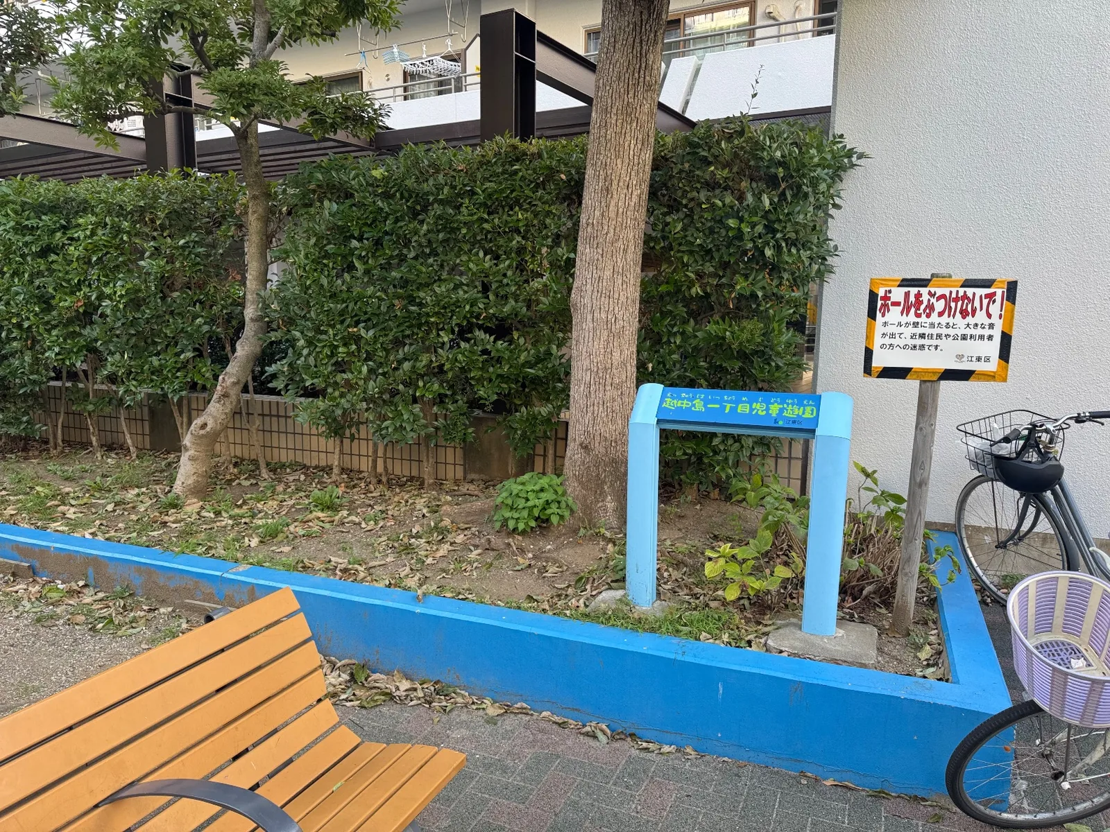 越中島一丁目児童遊園と書かれた水色の銘板と木のベンチ