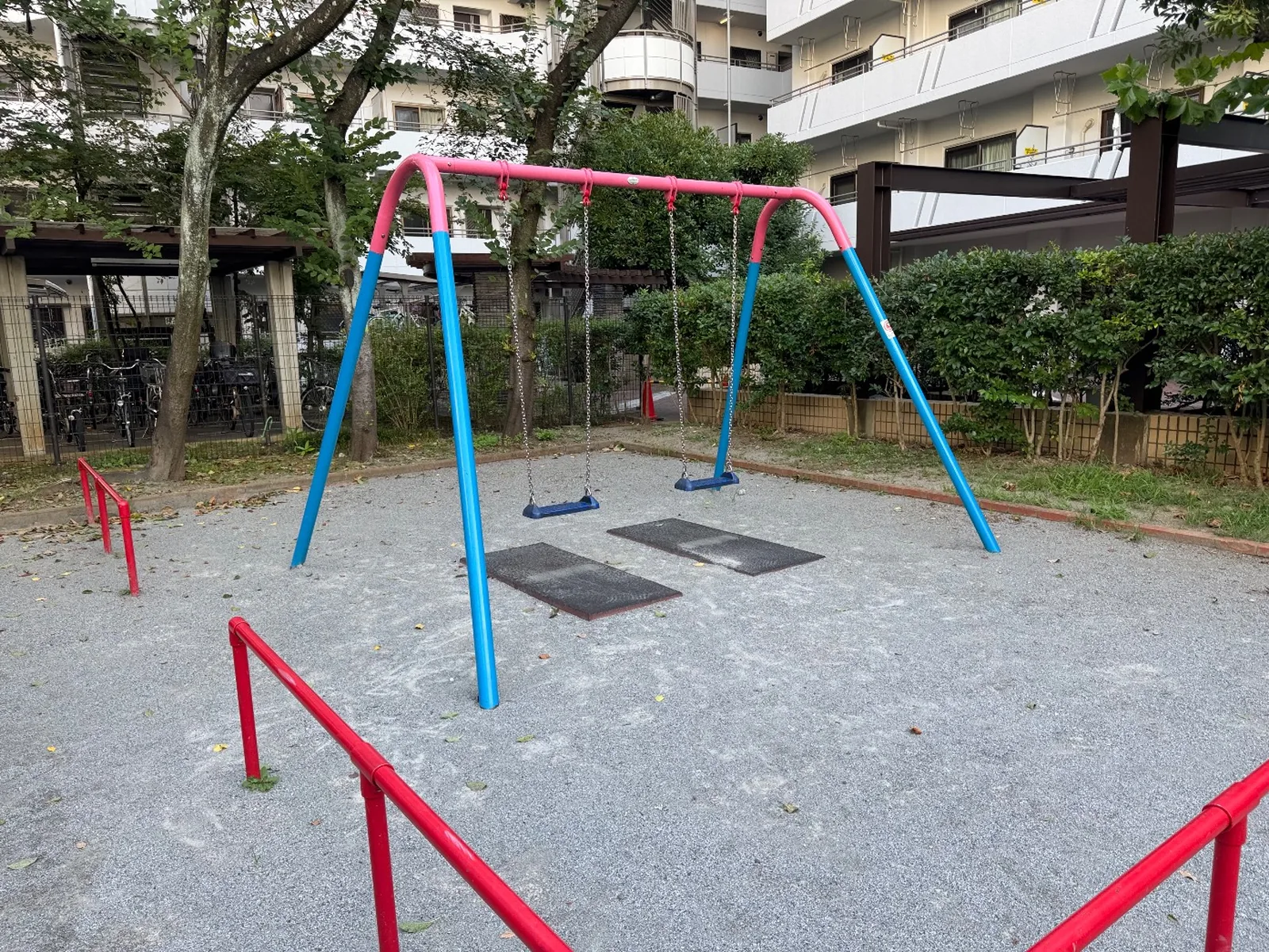 青い脚と赤い横木のブランコ。砂利の園