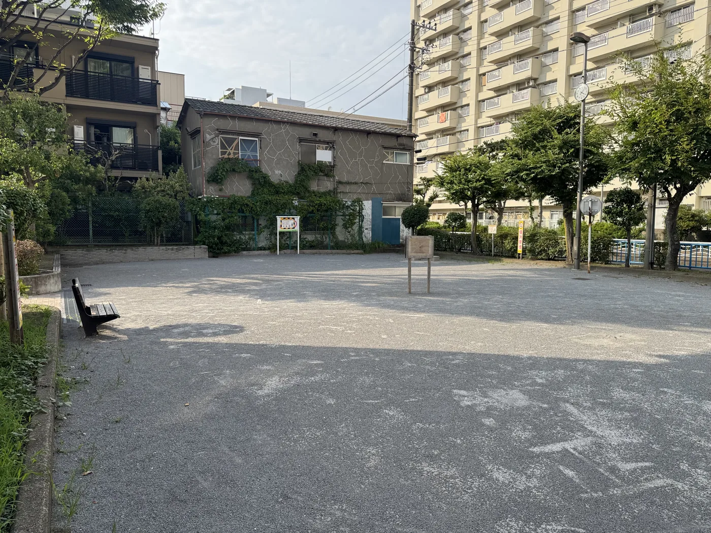 砂利の広場とベンチ。背後に住宅と高い集合住宅