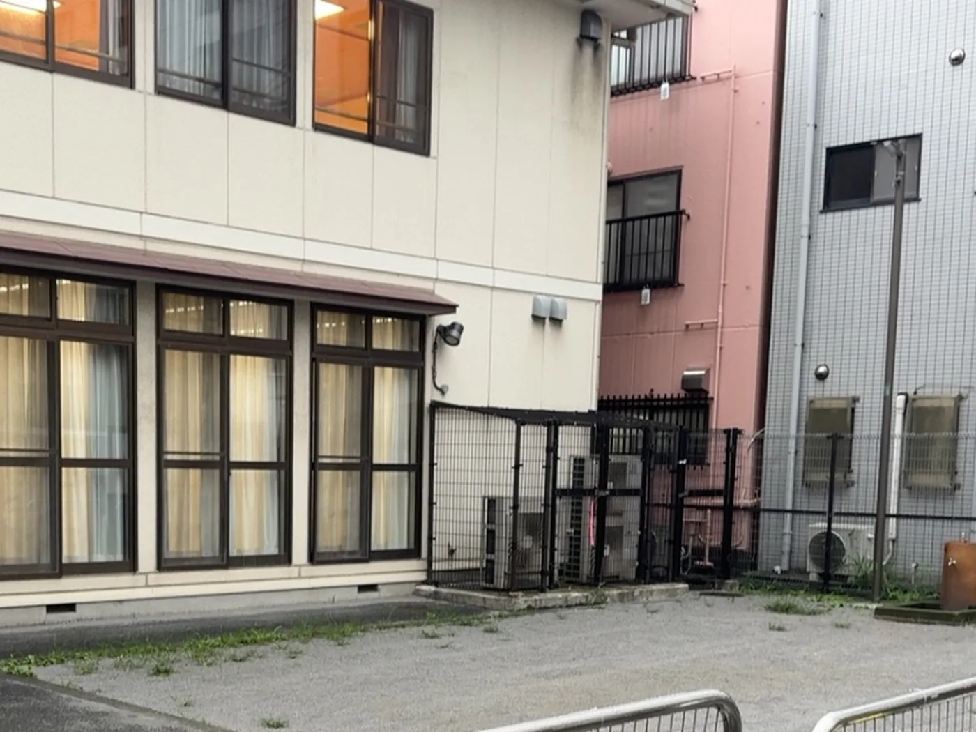 ベージュの二階建て建物の窓と、手前の砂利の地面
