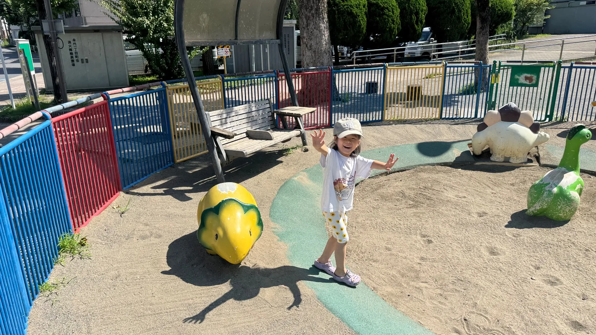 色とりどりの柵に囲まれた砂場と恐竜モチーフの遊具。永代公園の遊び場