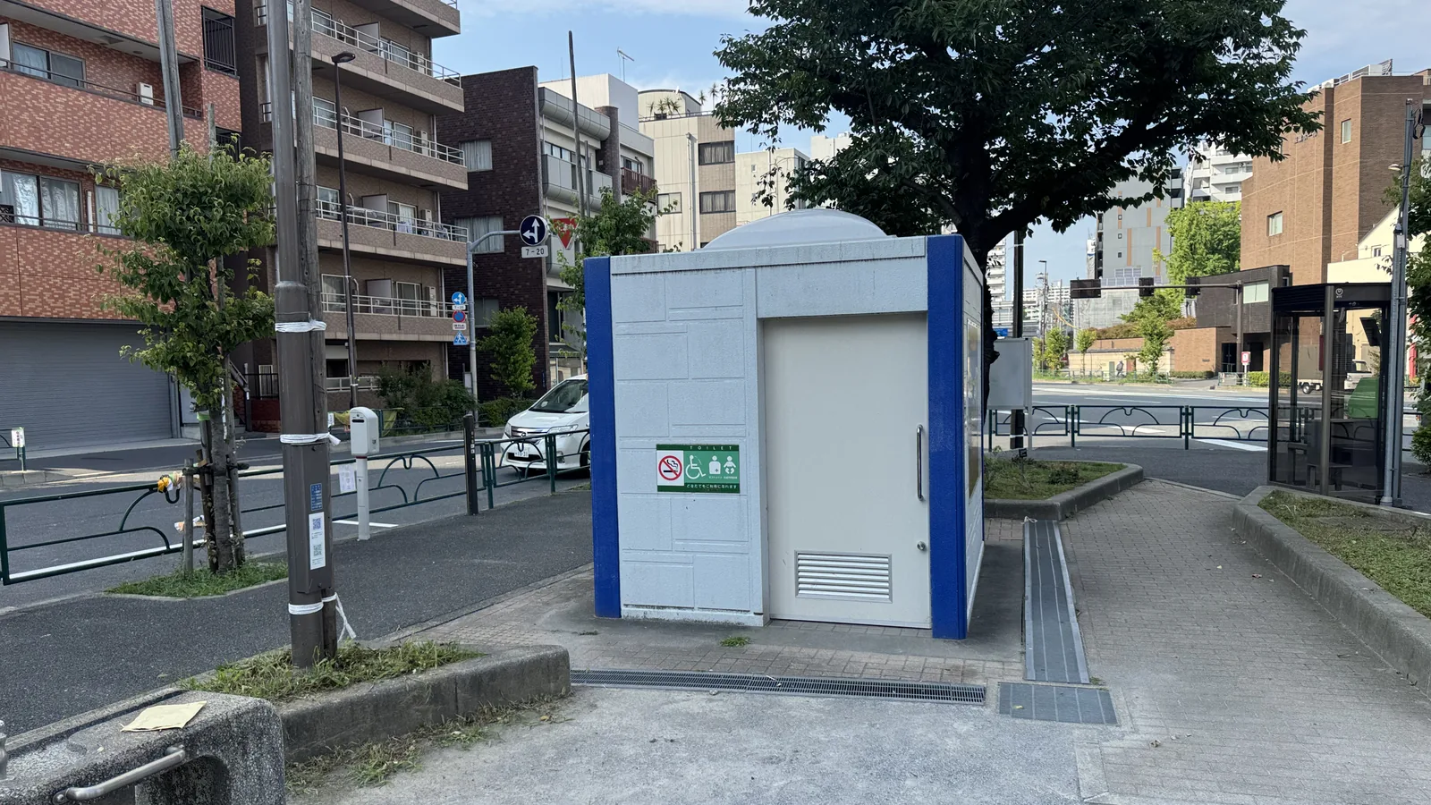 白と青のトイレ棟。車いす・おむつ替えの案内表示がある