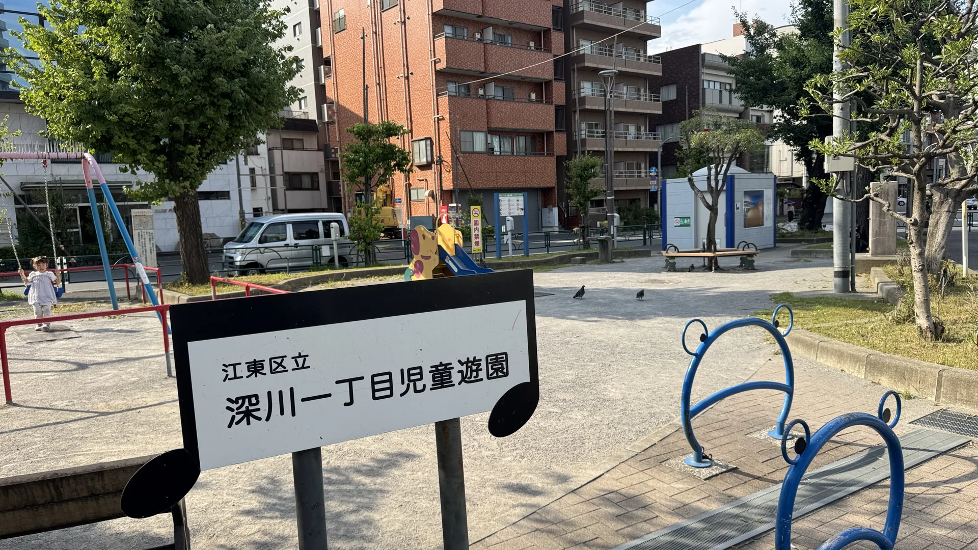 音符形の園名板とブランコ・すべり台が見える深川一丁目児童遊園の園内