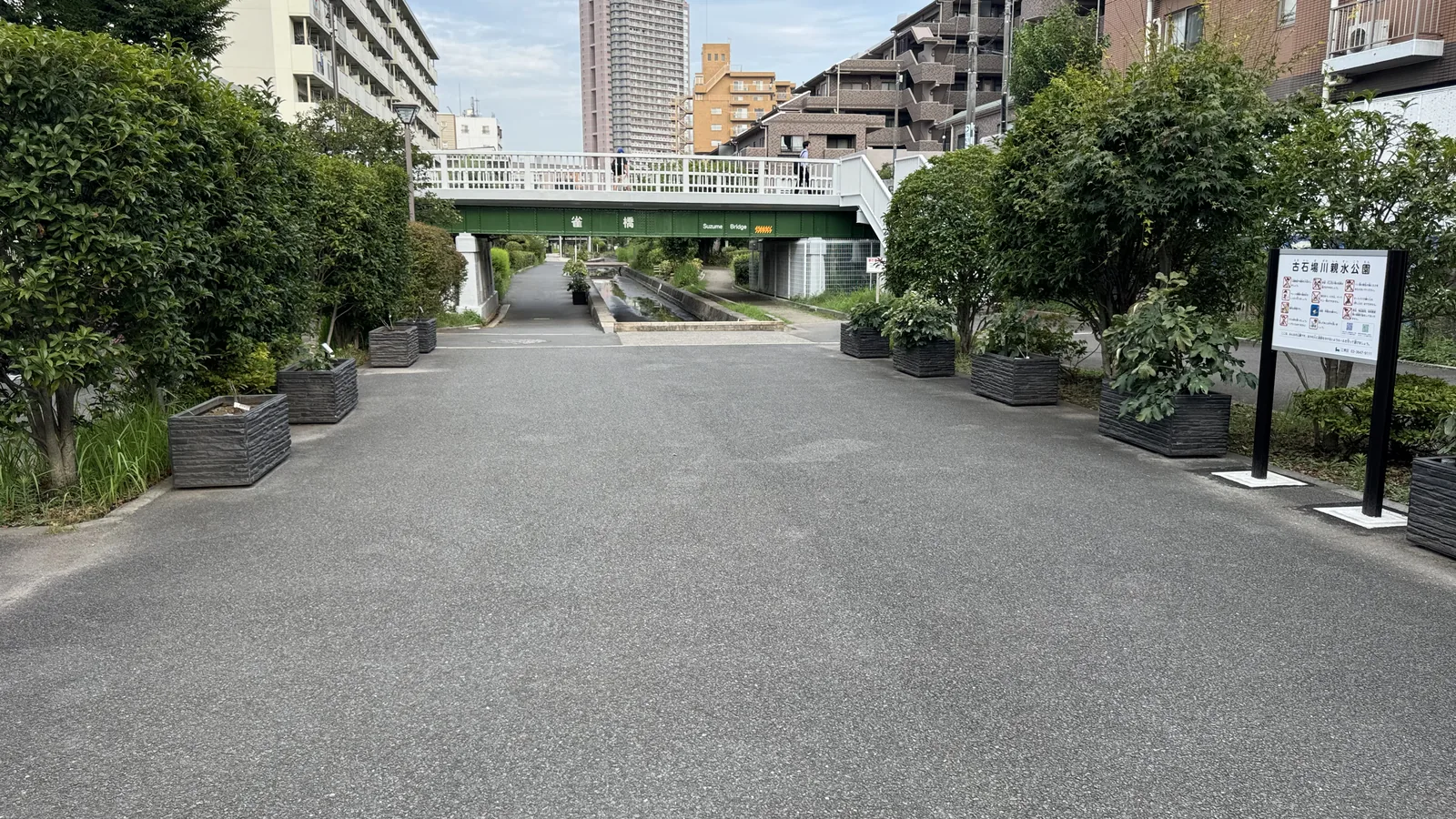 緑のプランターが並ぶ入口園路。奥に白い歩道橋
