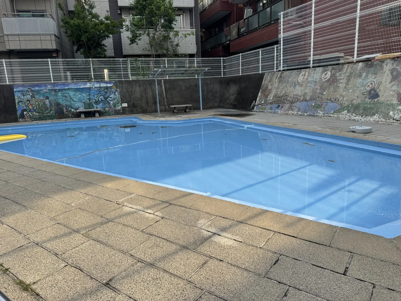 鮮やかな青い水面のじゃぶじゃぶ池。背後に壁画のある壁