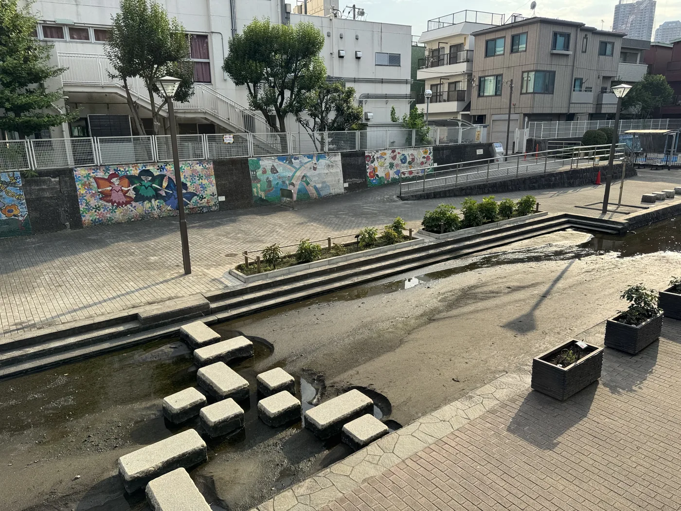 水路に並ぶ飛び石と階段状のテラス、壁画のある壁
