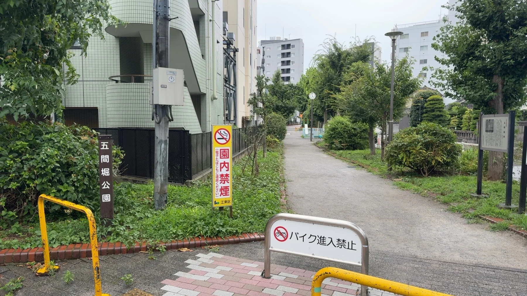 五間堀公園の名板と禁煙表示、細長い園路が奥へ続く景色