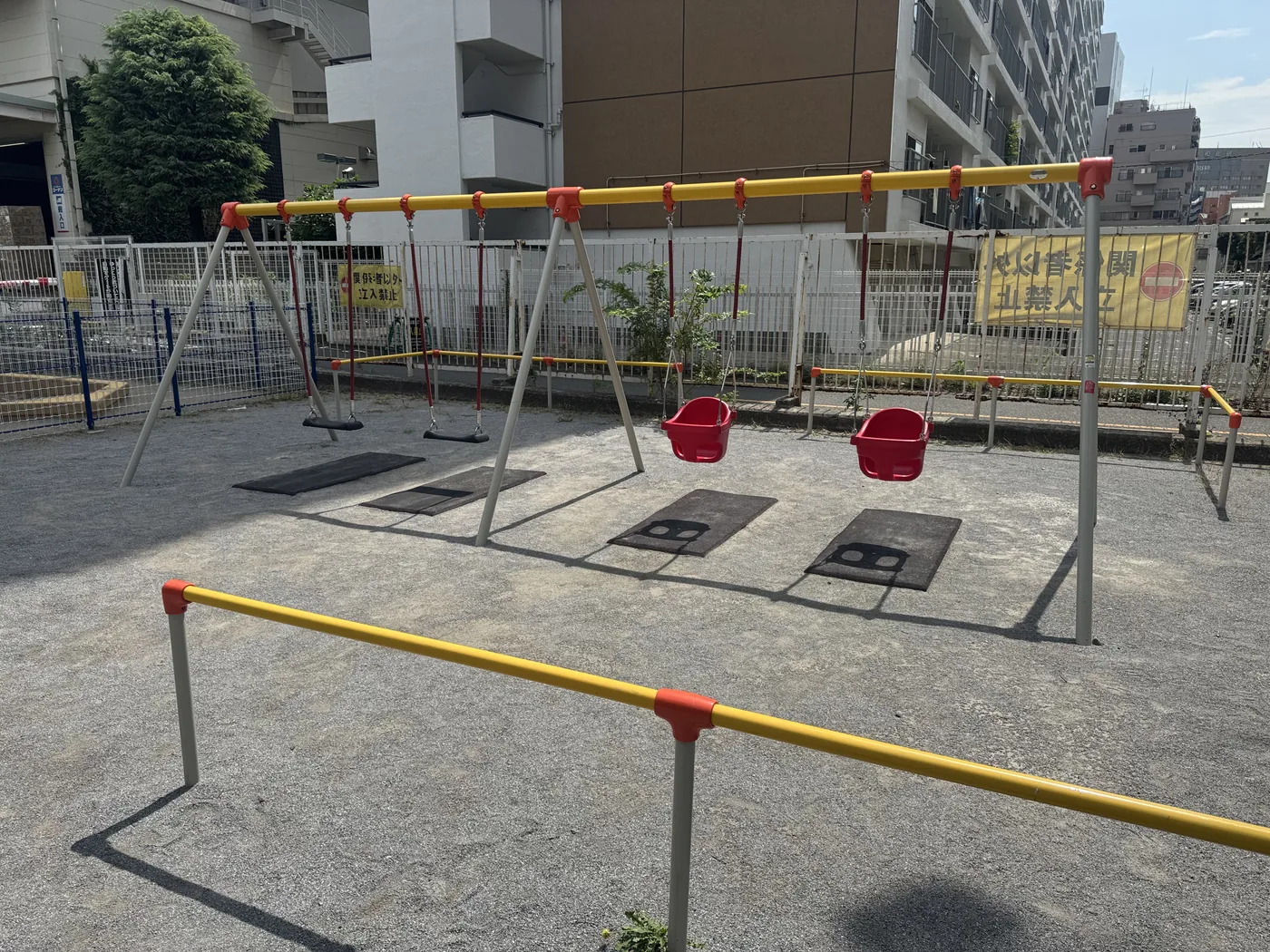 黄赤のフレームと4台のブランコがある遊具エリア