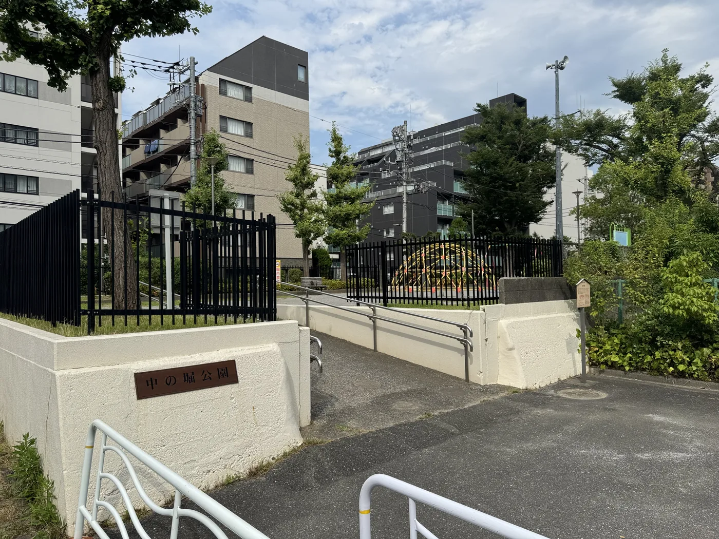 白い壁に埋め込まれた中の堀公園の銘板と入口スロープ