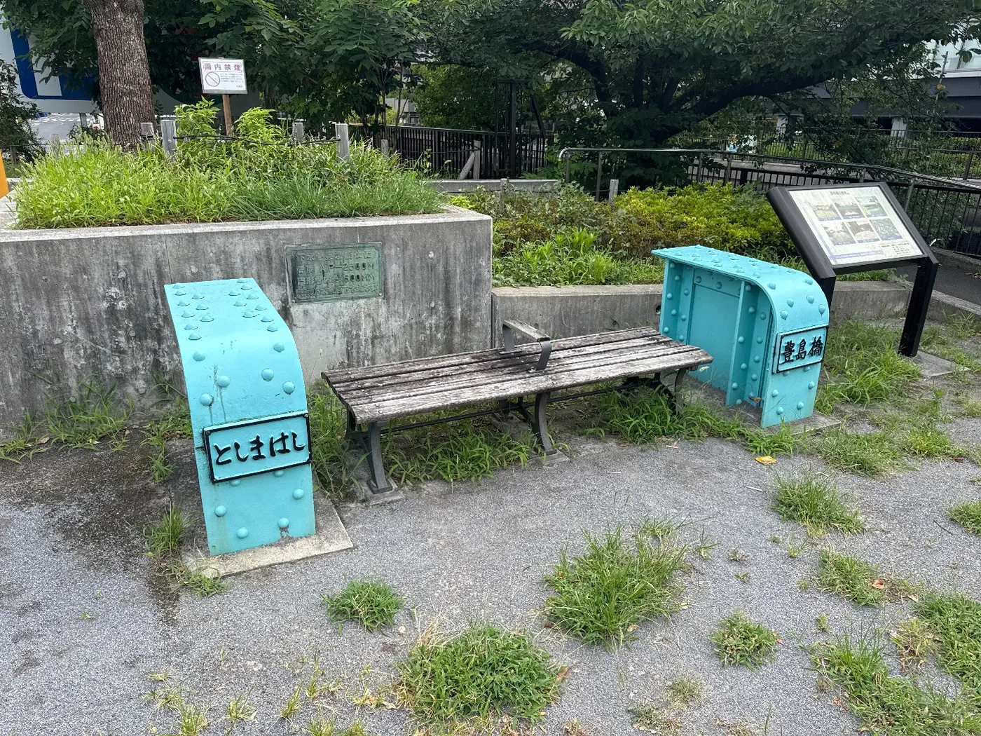 豊島橋の水色鋼材モニュメントに挟まれた木製ベンチと説明板