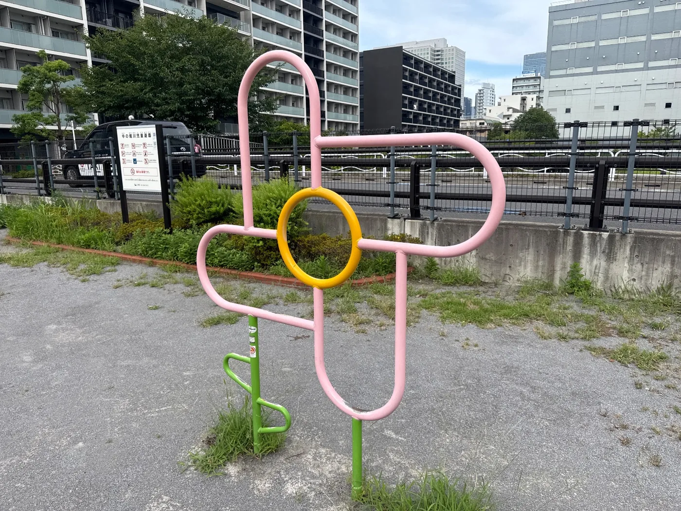 ピンクと黄の花形遊具と、背後の利用案内板