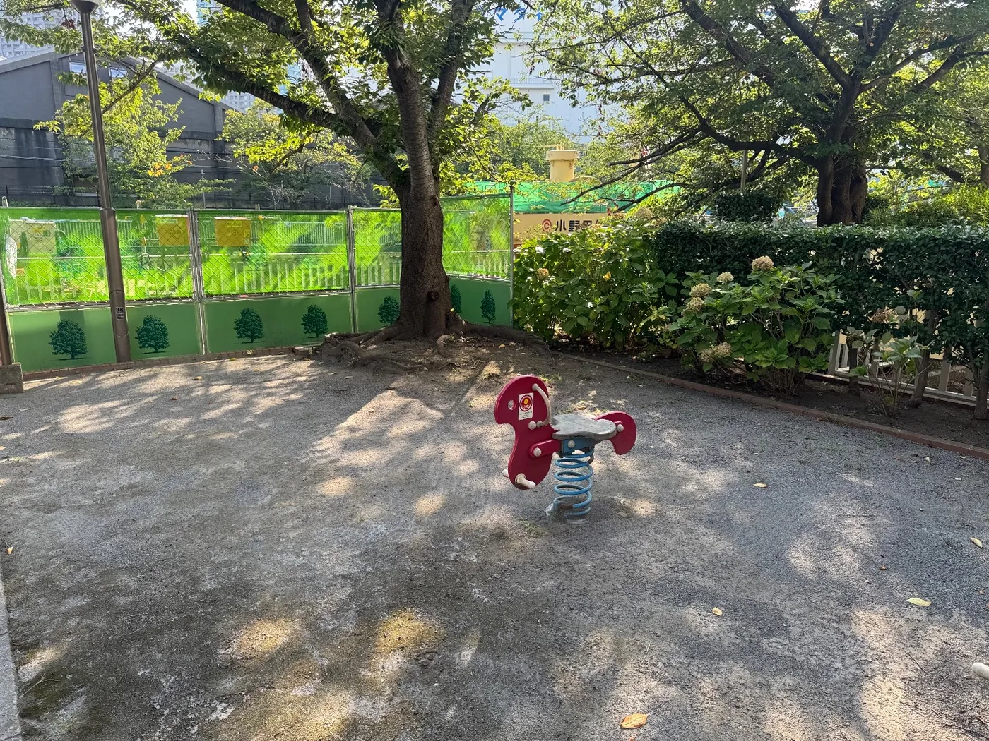 赤い馬型のスプリング遊具と木陰