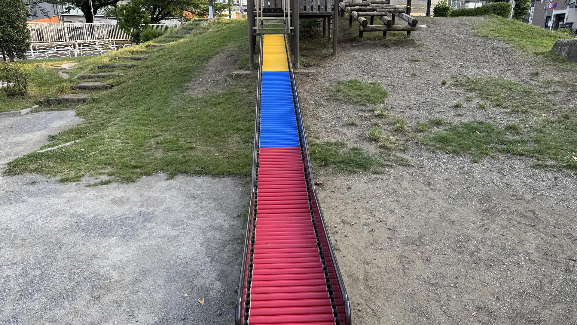丘に沿って伸びるカラフルなローラー滑り台がある臨海公園の遊具エリア