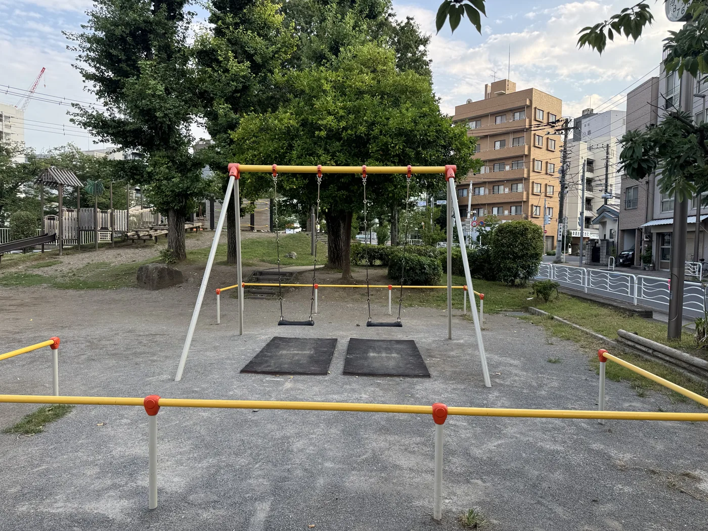 黄いフレームと2台のブランコがある遊具エリア