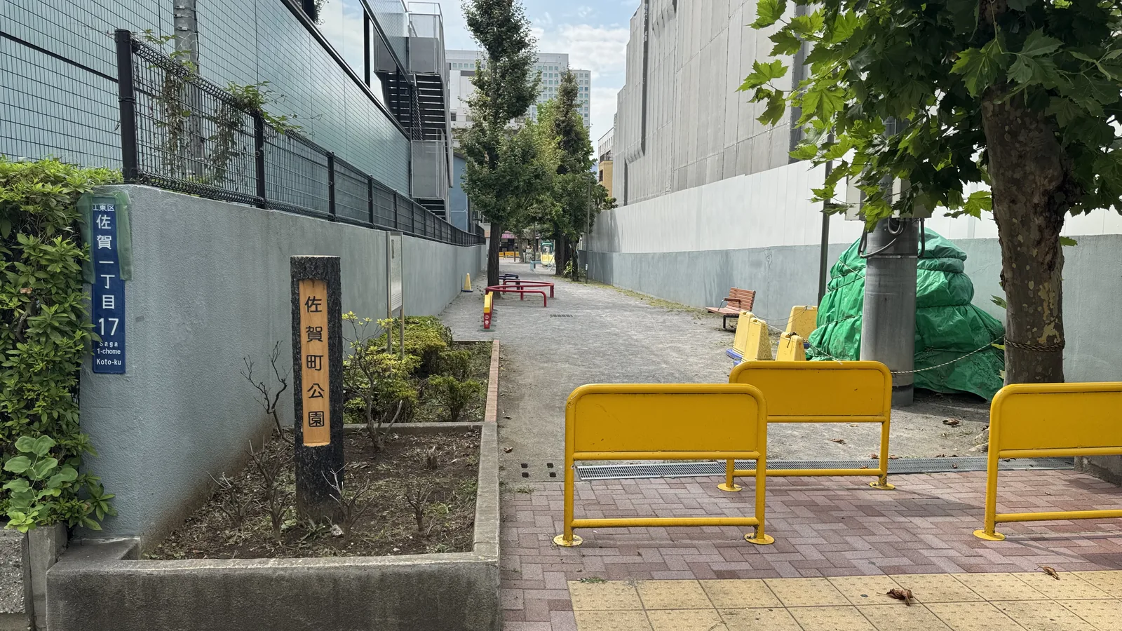佐賀町公園の入口。公園名板と黄色い車止め、触知ブロック