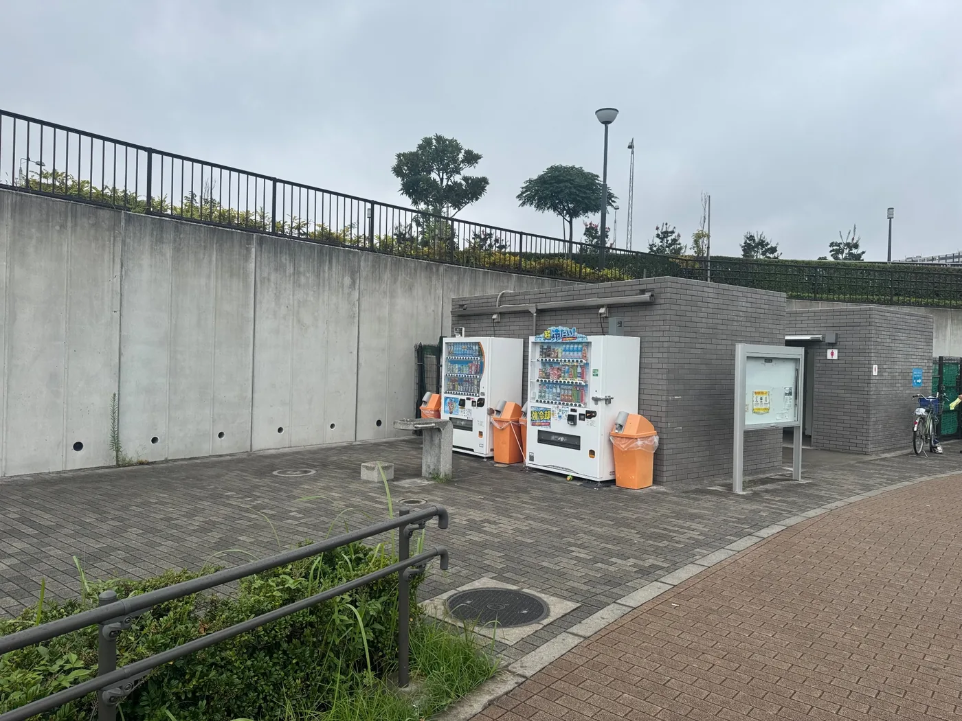 トイレ棟、自動販売機、水飲み場、ごみ箱が並ぶ園内施設