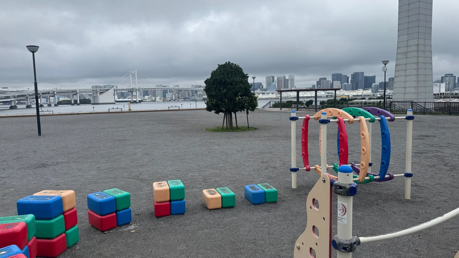 遊具の先に東京湾とレインボーブリッジが見える広場