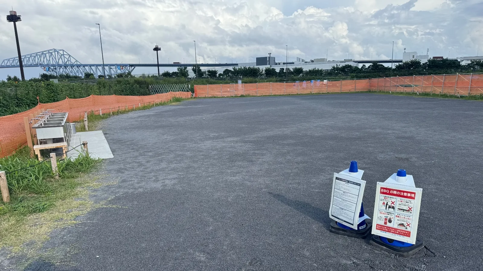 BBQ広場の広い地面と東京ゲートブリッジ。注意看板と流し台
