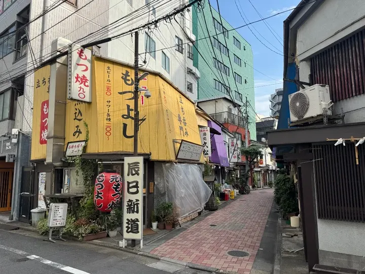 辰巳新道の看板と店先が並ぶ日中の路地入口