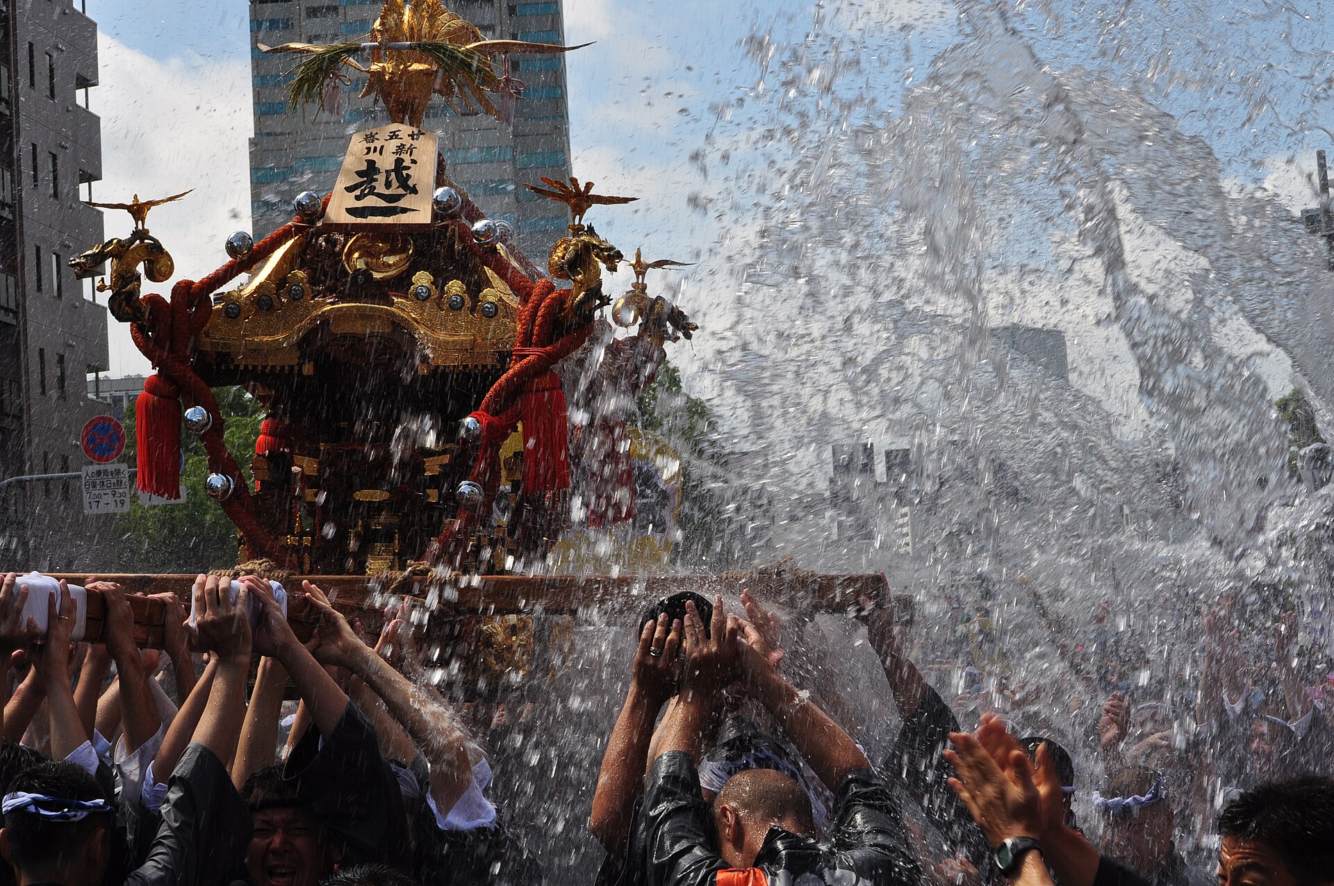 神輿と担ぎ手へ大量の水が勢いよく浴びせられる深川祭の水かけ。