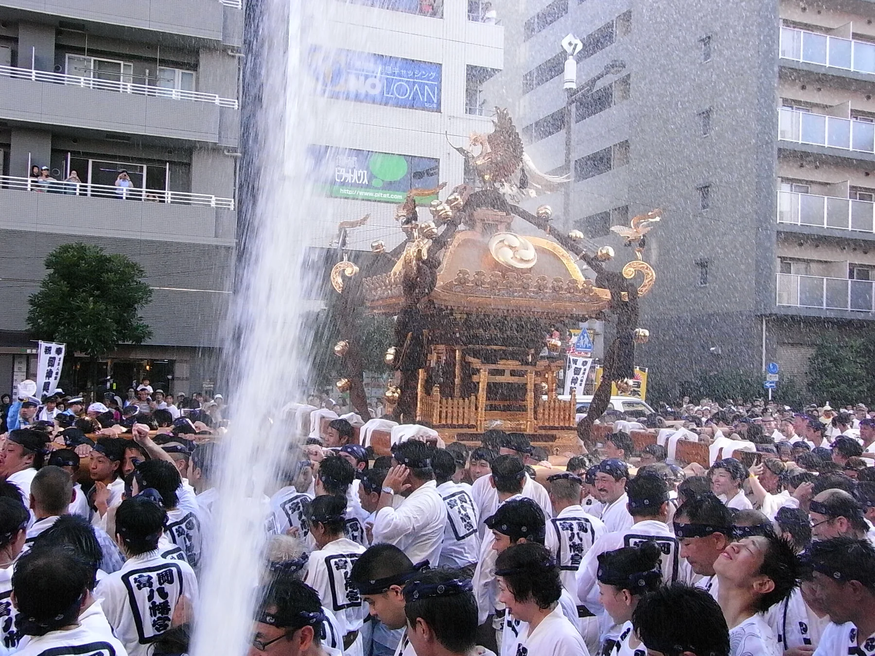 大量の清めの水を浴びながら進む御本社神輿と担ぎ手